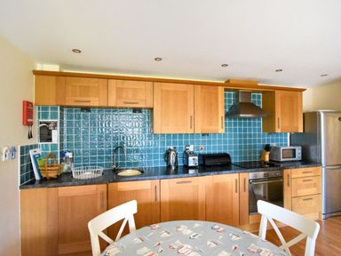 A kitchen with wooden cabinets blue tiled backsplash and appliances at 2 Buckfields Lyme Regis