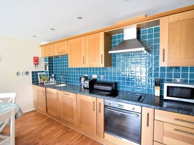 A kitchen with wooden cabinets blue tiled backsplash and various appliances at 2 Buckfields in Lyme Regis