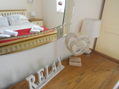 Decorative hearts and a relax sign on a wooden dresser with a bed reflected in the mirror at 2 Buckfields in Lyme Regis