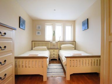 A bedroom with two single beds separated by a nightstand with a lamp at 2 Buckfields Lyme Regis