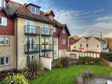 An apartment building with balconies and a garden with benches at 2 Buckfields in Lyme Regis