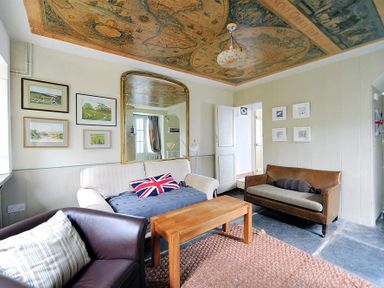 A living room with sofas a wooden coffee table wall art and a ceiling map at 10 Cobb Terrace in Lyme Regis