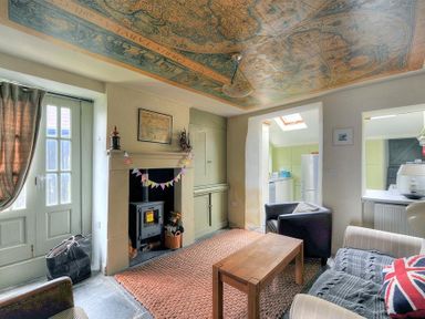 A living room with a wood stove in the fireplace a wooden coffee table two armchairs and a sofa with a blanket and cushion at 10 Cobb Terrace in Lyme Regis