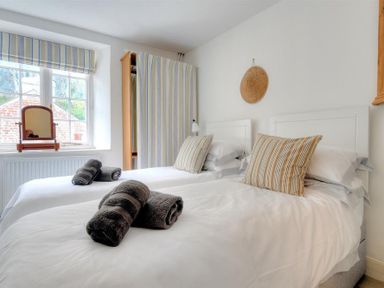 A bedroom with two single beds pillows and rolled towels at 10 Cobb Terrace in Lyme Regis
