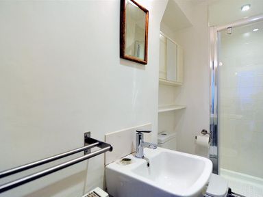 A bathroom with a sink faucet mirror towel rack toilet paper holder and a glass shower at 10 Cobb Terrace Lyme Regis