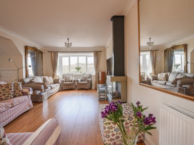 A living room with sofas cushions a fireplace and flowers on a table at Jurassic Sea View in Lyme Regis