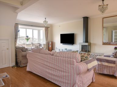 A living room with striped sofas a wall-mounted tv and a fireplace at Jurassic Sea View in Lyme Regis
