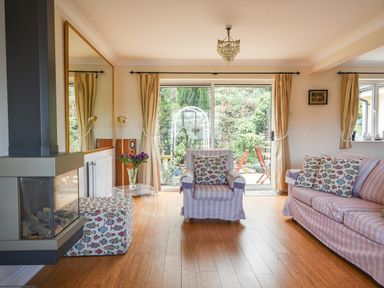 A living room with a fireplace armchair sofa and glass door leading to a garden at Jurassic Sea View Lyme Regis