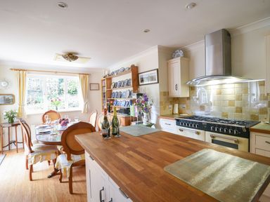 A kitchen with wooden countertops a dining table with chairs and a cupboard with plates at Jurassic Sea View Lyme Regis