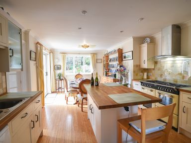 A kitchen with wooden island and dining table with chairs near window at Jurassic Sea View in Lyme Regis