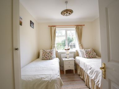 A bedroom with two single beds pillow with fish patterns bedside table between beds and window with curtains at Jurassic Sea View in Lyme Regis