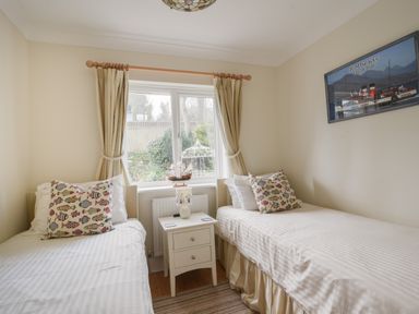 A bedroom with two single beds a window between and a bedside table with a lamp at Jurassic Sea View Lyme Regis