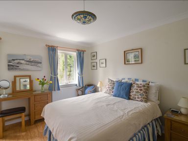 A bedroom with a bed a wooden desk and blue curtains at Jurassic Sea View in Lyme Regis