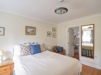 A bedroom with a bed pillows on bed bedside tables a chair wall art and a mirror at Jurassic Sea View in Lyme Regis