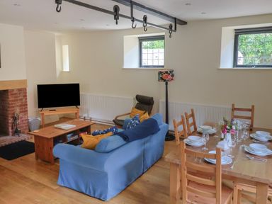 A living room with a sofa, television, and dining table at Yard Cottage in Rousdon