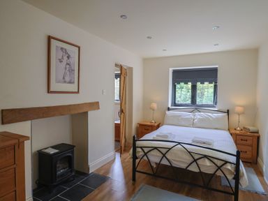 A bedroom with a bed and nightstands at Yard Cottage in Rousdon