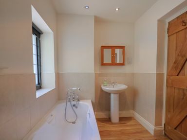 A bathroom with a bathtub and sink at Yard Cottage in Rousdon