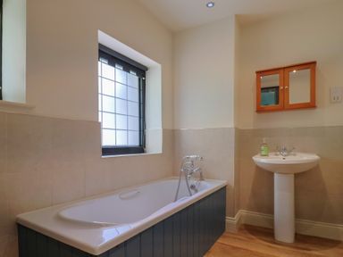 A bathroom with a bathtub and a washbasin at Yard Cottage, Rousdon