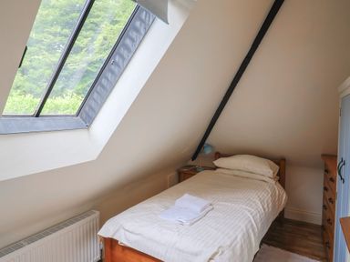 A bedroom with a single bed and a window at Yard Cottage in Rousdon