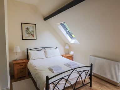 A bedroom with a bed and nightstands at Yard Cottage in Rousdon