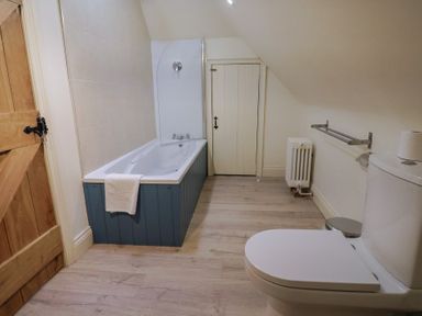 A bathroom with a bathtub and toilet at Yard Cottage in Rousdon