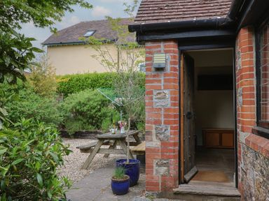 A garden with a table and chairs at Yard Cottage in Rousdon