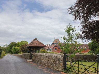 A view of a road leading to a house with a stone wall and trees at Yard Cottage in Rousdon
