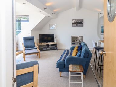 A living room with blue sofas a wooden chair a television and a fireplace at The Penthouse in Lyme Regis