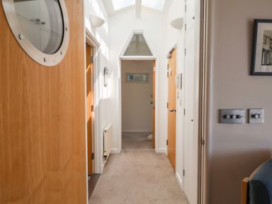 A hallway with wooden doors and white walls and ceiling at The Penthouse in Lyme Regis