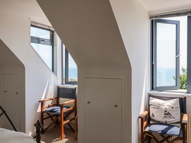 A room with two wooden chairs near two windows overlooking the sea at The Penthouse in Lyme Regis