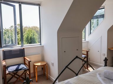 A bedroom corner with two wooden chairs and small round table by windows under sloped ceilings at The Penthouse in Lyme Regis