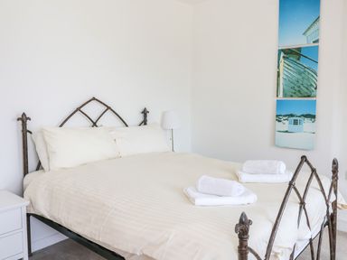A bedroom with a bed with white sheets and pillows and folded towels on top at The Penthouse in Lyme Regis