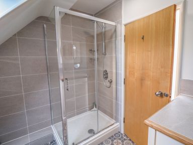A bathroom with a glass enclosed shower next to a wooden door and a countertop at The Penthouse in Lyme Regis