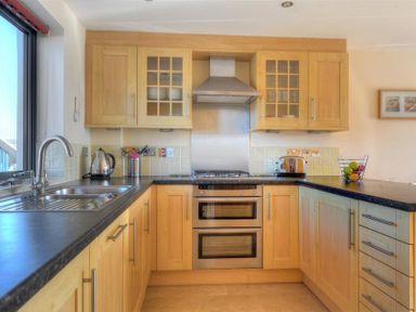 A kitchen with wooden cabinets a stainless steel sink a kettle toaster and a fruit bowl at 8 Driftwood West Bay