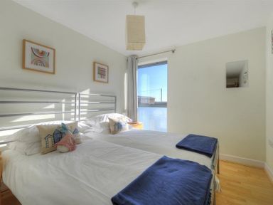 A bedroom with two single beds side by side with white bedding and blue throws at 8 Driftwood in West Bay