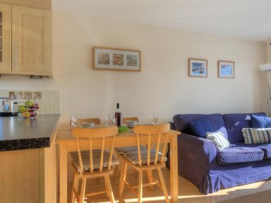 A dining area with a wooden table and chairs next to a purple sofa in a living space at 8 Driftwood in West Bay