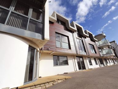 The exterior of a modern building with large windows and balconies at 8 Driftwood in West Bay