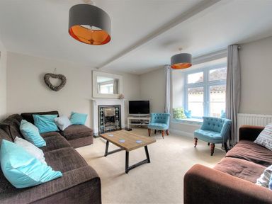 A living room with sofas a coffee table two blue chairs and a window seat at Mermaid House in Lyme Regis