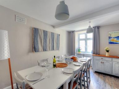 A dining room with a white table set for six with plates and wine glasses at Mermaid House in Lyme Regis