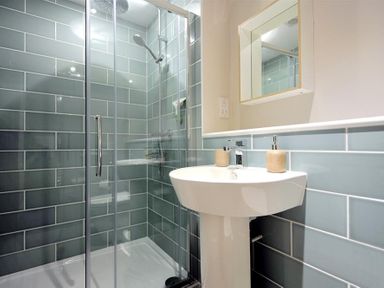 A bathroom with a glass shower enclosure a sink with two soap dispensers and a mirror cabinet at Mermaid House in Lyme Regis