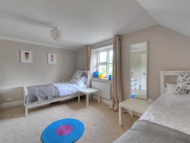 A bedroom with two single beds a window with curtains a mirror and two small tables at Mermaid House in Lyme Regis