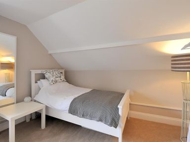 A bedroom with a single bed a bedside table a floor lamp and a mirror at Mermaid House in Lyme Regis