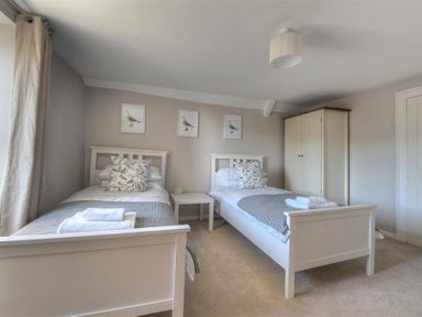 A bedroom with two single beds a nightstand and a wardrobe at Mermaid House in Lyme Regis