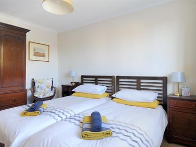 A bedroom with two single beds bedside tables lamps a wooden wardrobe and a chair at Woody View in Colyton