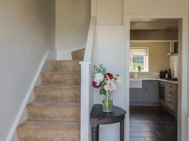 A hallway with a staircase leading to upper floors and a view into the kitchen at Westhaven in Lyme Regis