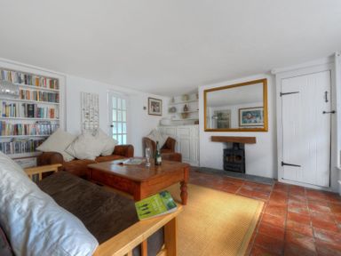 A living room with wooden furniture a bookcase and a fireplace at 24 Mill Green in Lyme Regis