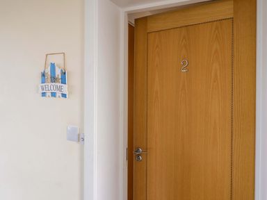 A wooden door with number 2 and a welcome sign on the adjacent wall at 2 Driftwood in West Bay