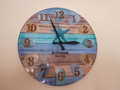 A wall clock with numbers on stones and a starfish design at 2 Driftwood in West Bay