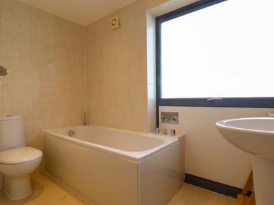 A bathroom with a bathtub toilet and sink near a frosted window at 2 Driftwood in West Bay