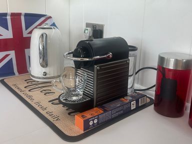 A coffee machine with a kettle and coffee cup at High Bullen Lodge Morcombelake